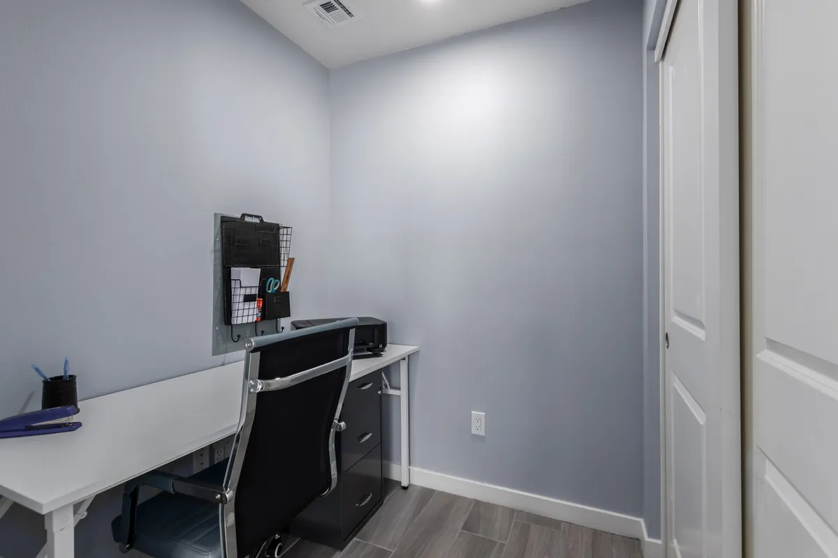 A tidy and productive office space featuring a desk, chair, and organization board. The setup is designed for focus, allowing guests to blend business with pleasure in a quiet corner of the home.