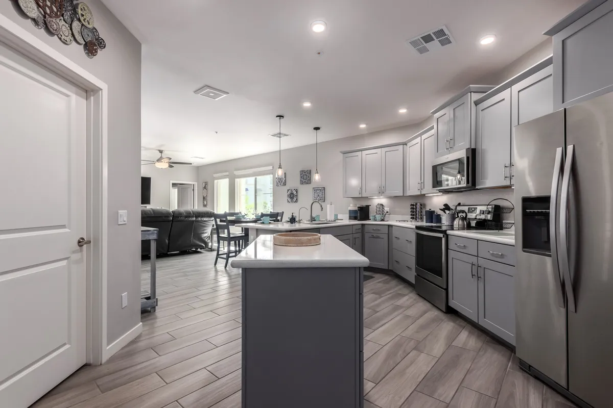 A modern open-plan kitchen and dining area featuring a kitchen island, stainless steel appliances, and decorative wall art. The layout highlights the seamless flow between cooking and dining spaces, ideal for entertaining and family gatherings.